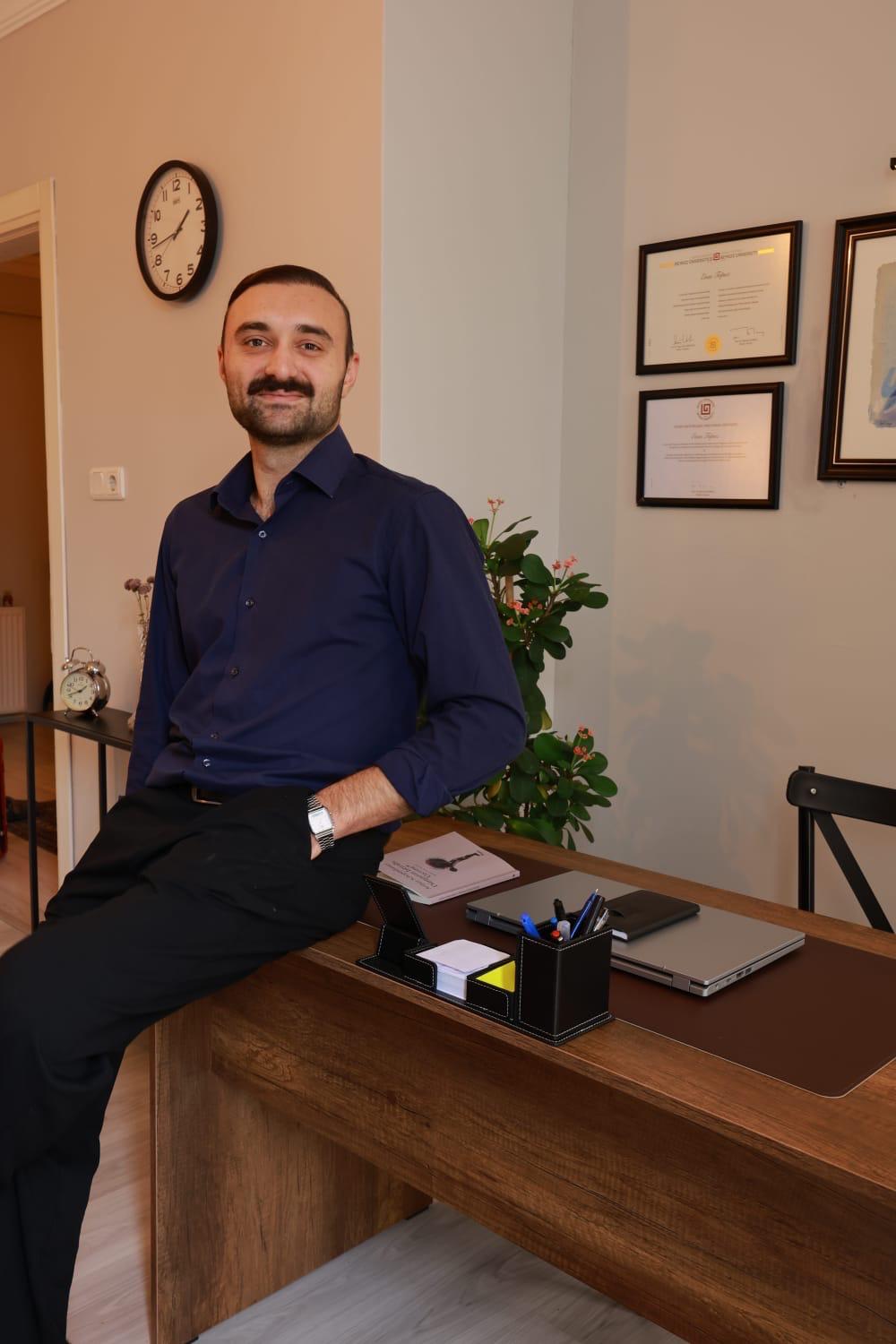 Klinik Psikolog Enes Topuz ofisinde ayakta poz verirken